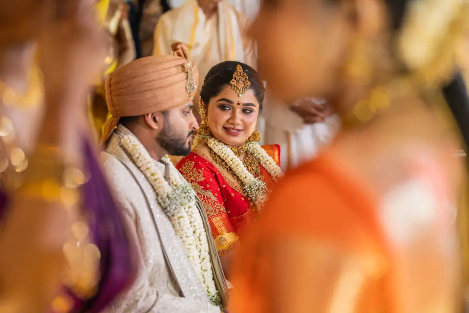 The couple smiling through a soft blur of orange silk in the foreground