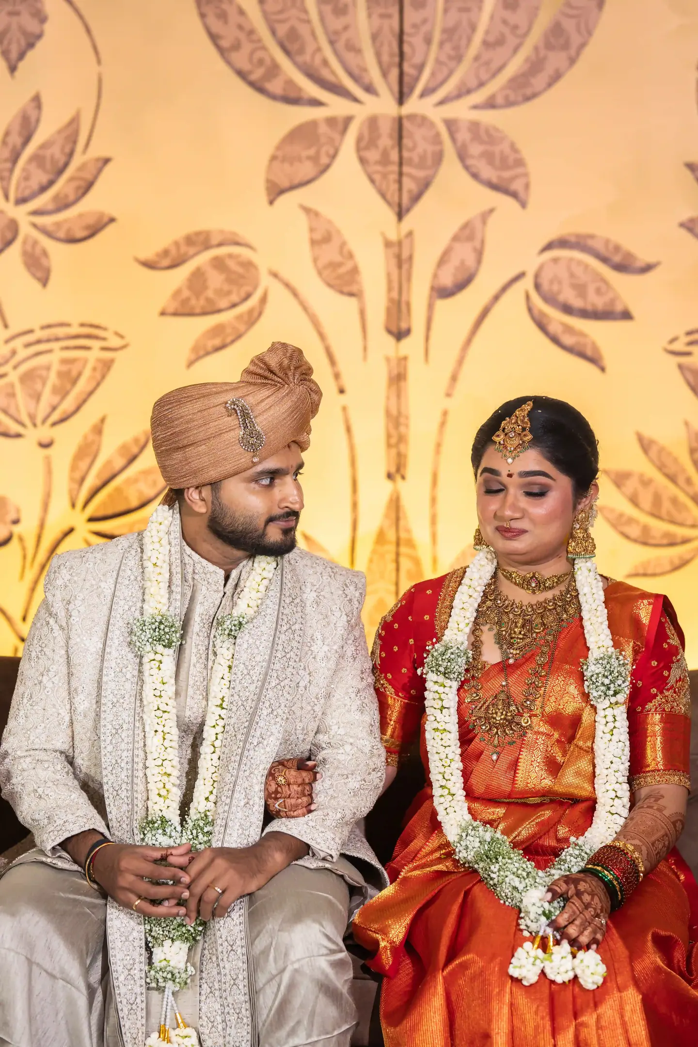 The couple seated side by side in garlands