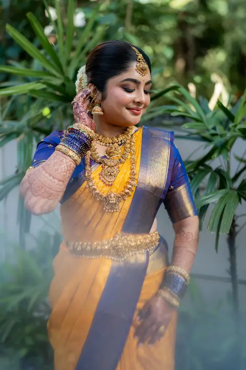 Kavya in yellow silk among garden leaves