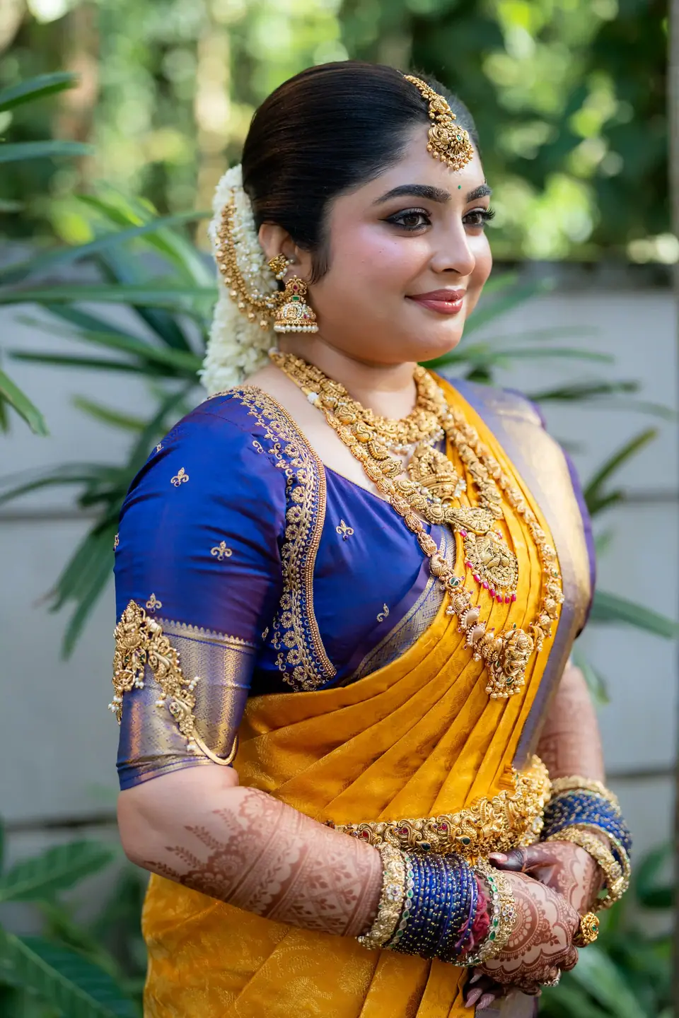 The bride smiling in the garden, gold jewellery bright against blue silk