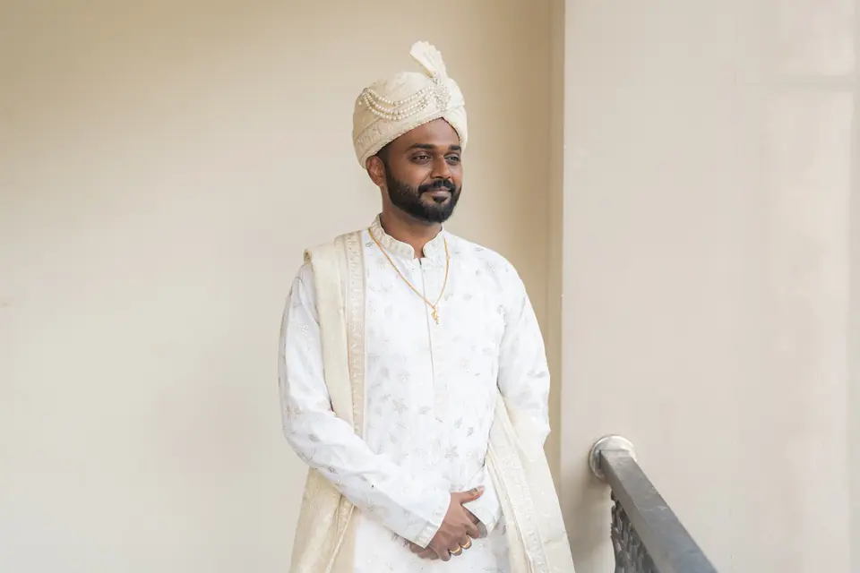 The groom in ivory standing in a quiet corridor