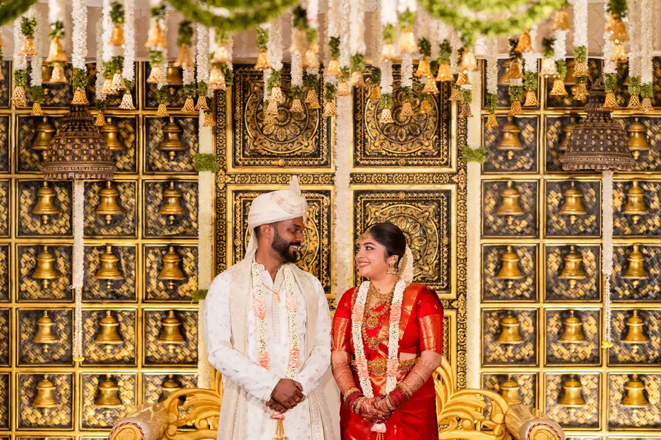 The couple standing at either end of a wall of gold carvings
