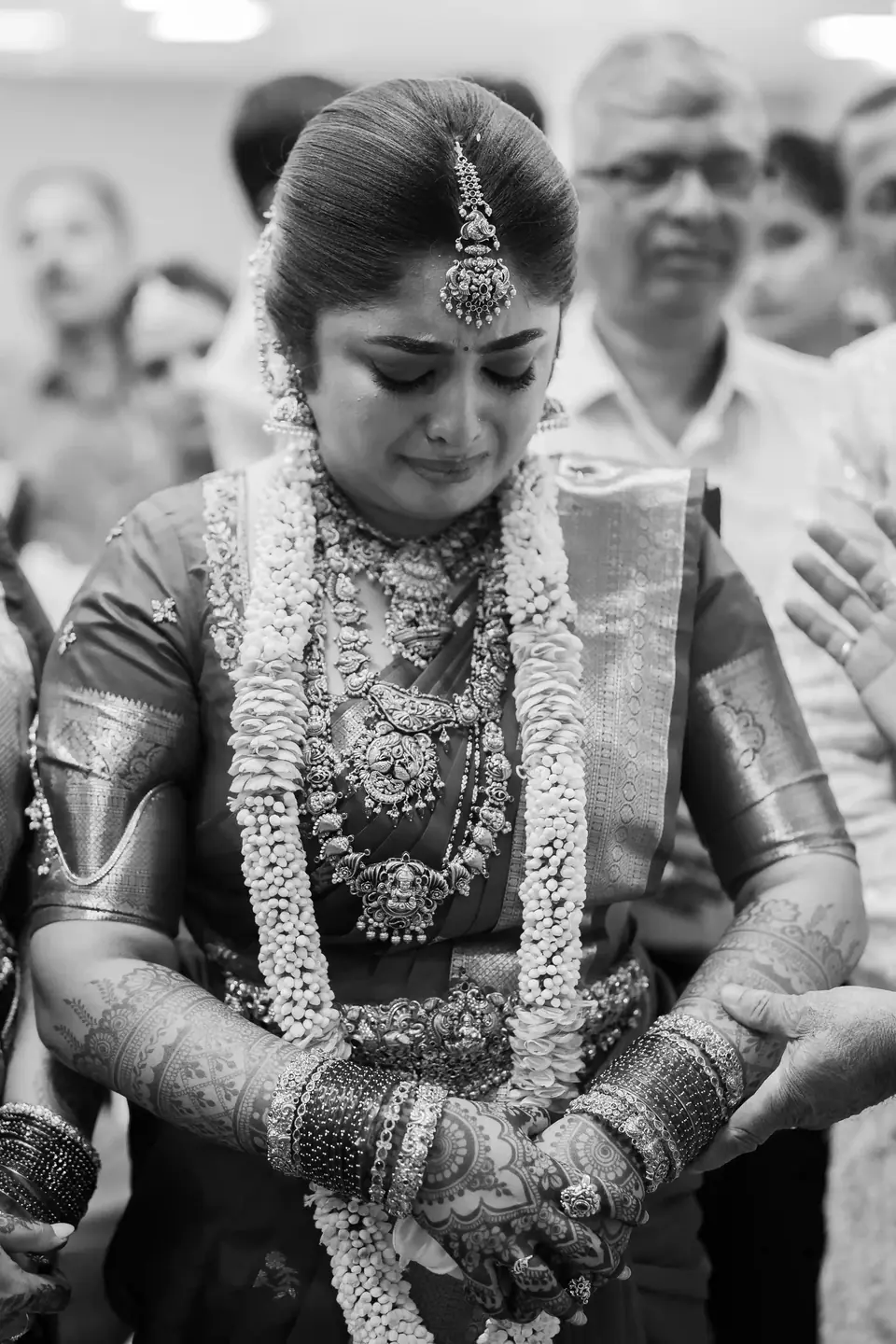 Black and white: the bride in tears, head bowed, as relatives reach for her