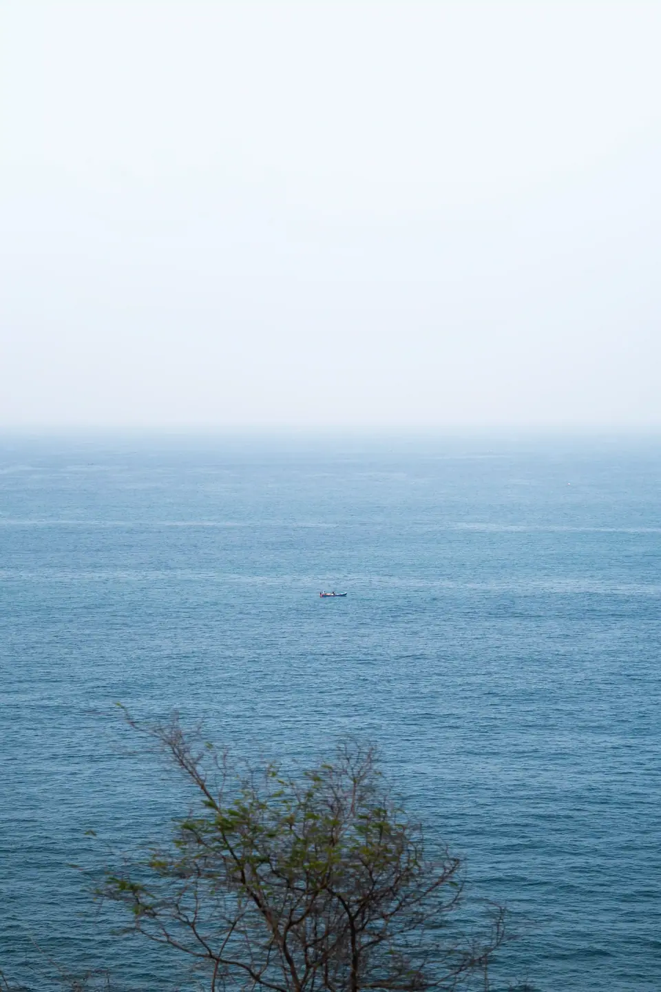 The sea, calm and pale blue, seen from the cliff edge