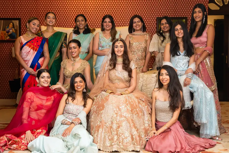 The bride laughing on a sofa, surrounded by her friends in pastel and red