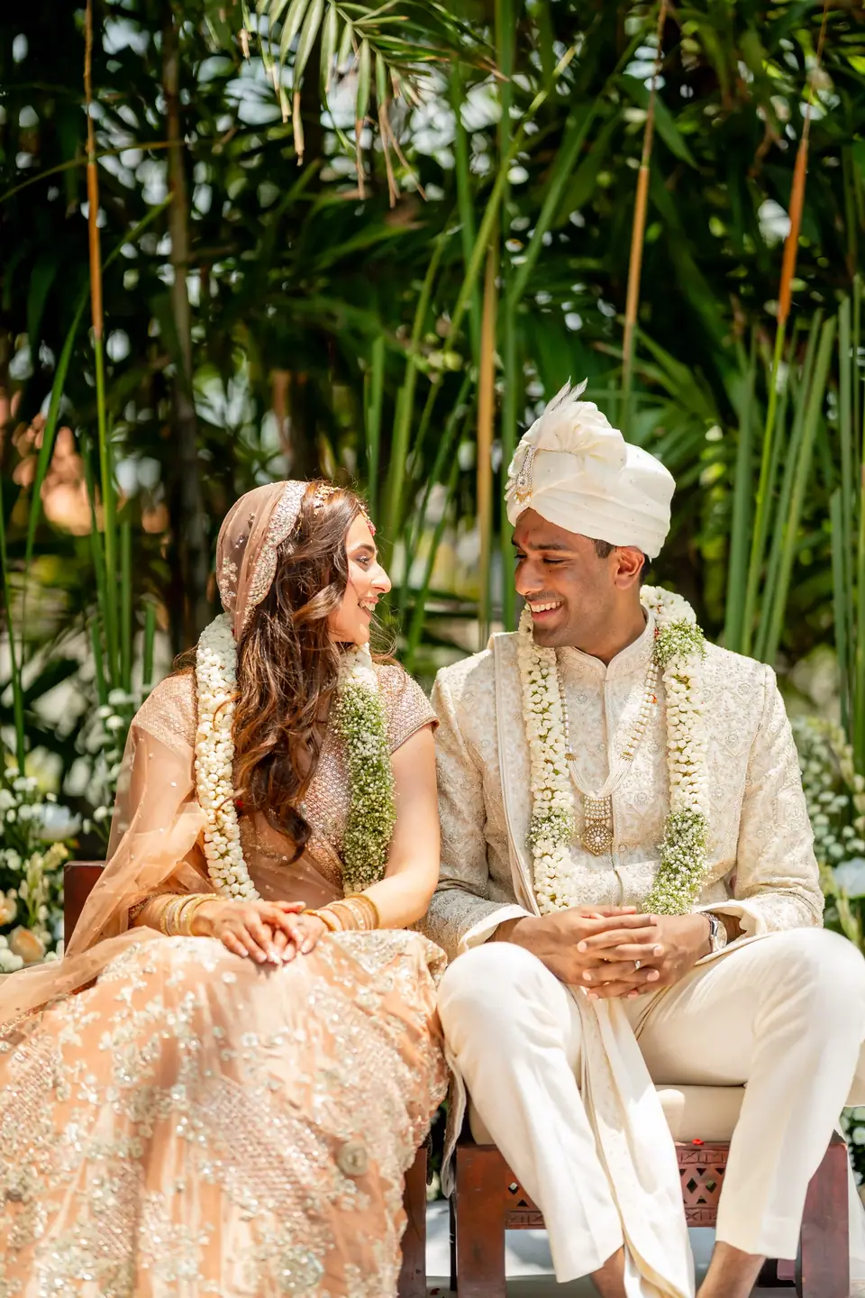 Kabir and Rhea seated in the mandap, turning to each other and laughing