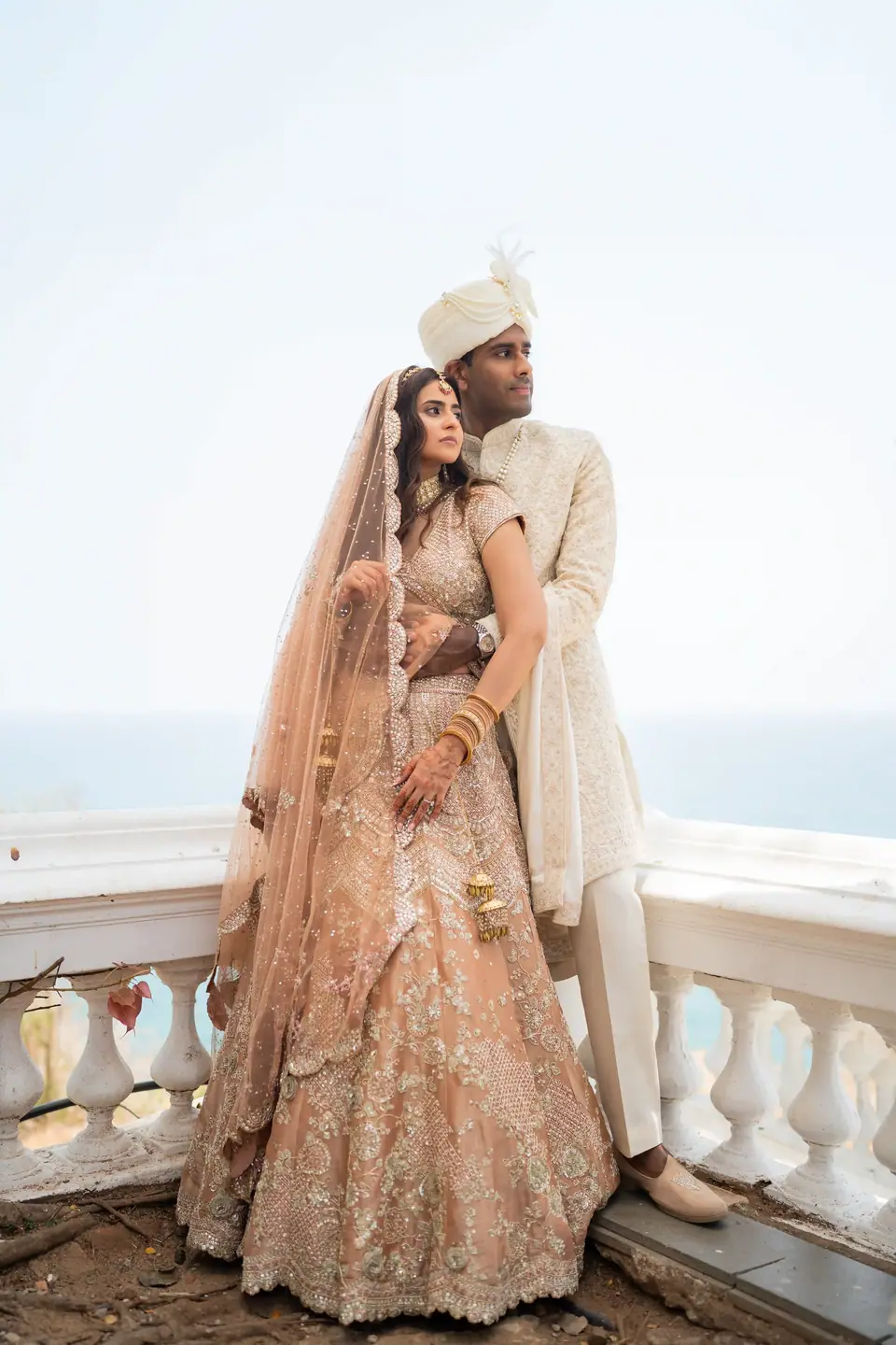 The couple standing together at a white balustrade above the sea