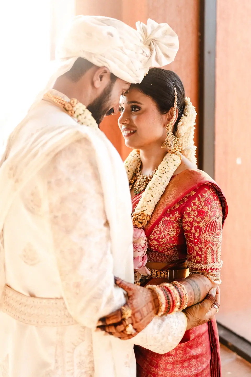 The groom resting his forehead against the bride's, both smiling