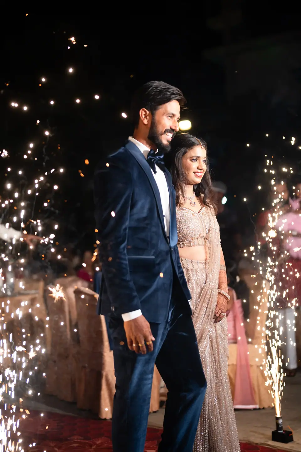 The couple walking between showers of sparklers at night