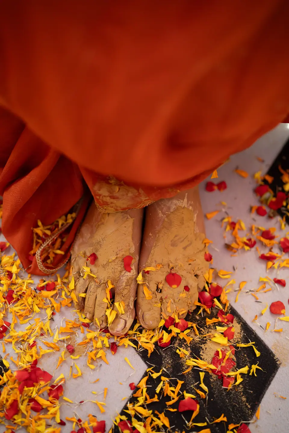Detail of the bride's turmeric-stained feet among marigold petals