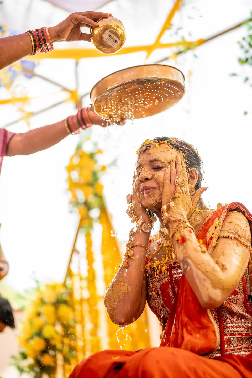 Water poured over the bride from a brass sieve as she laughs