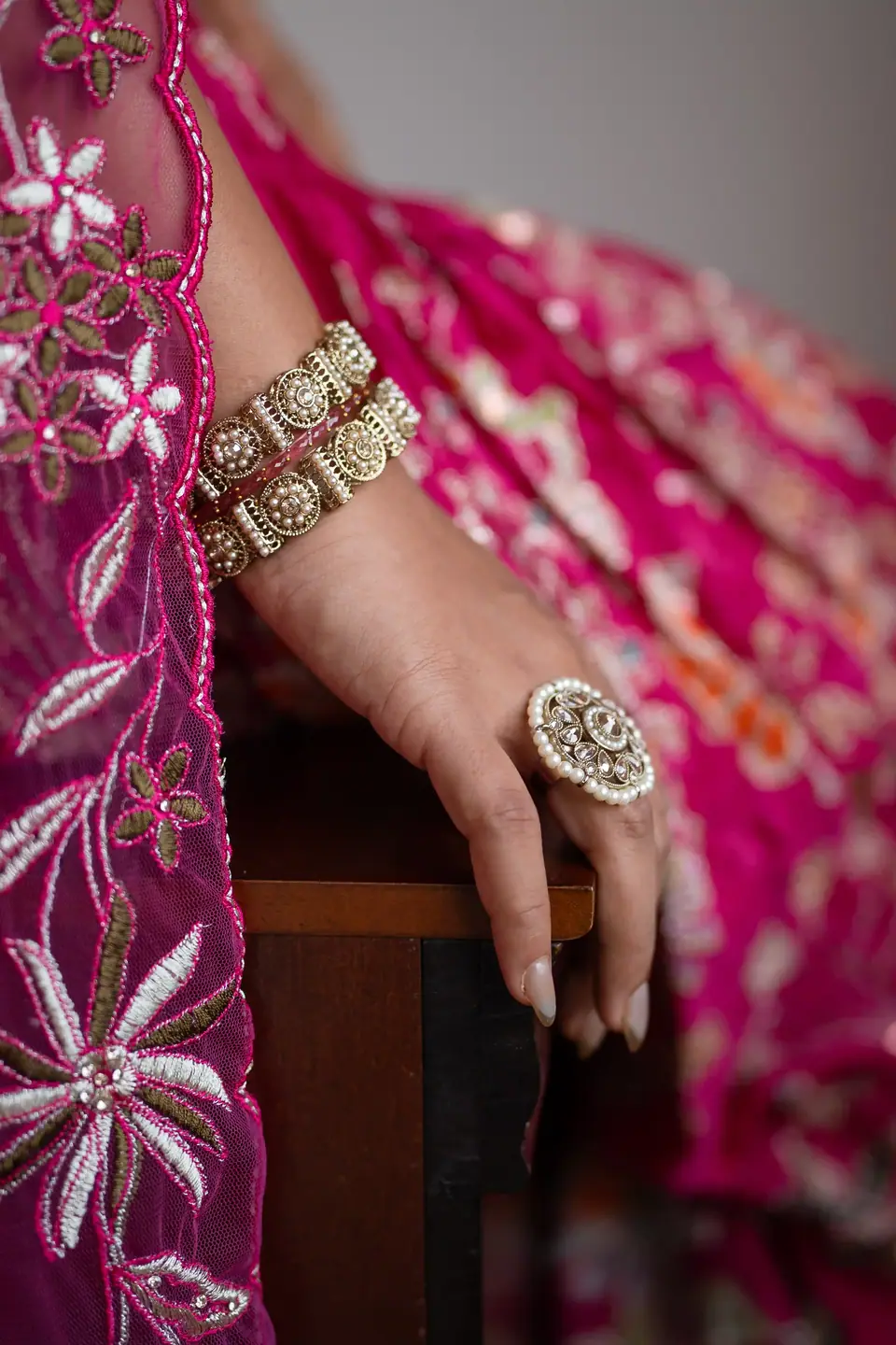 Detail of a ringed hand resting on embroidered pink fabric