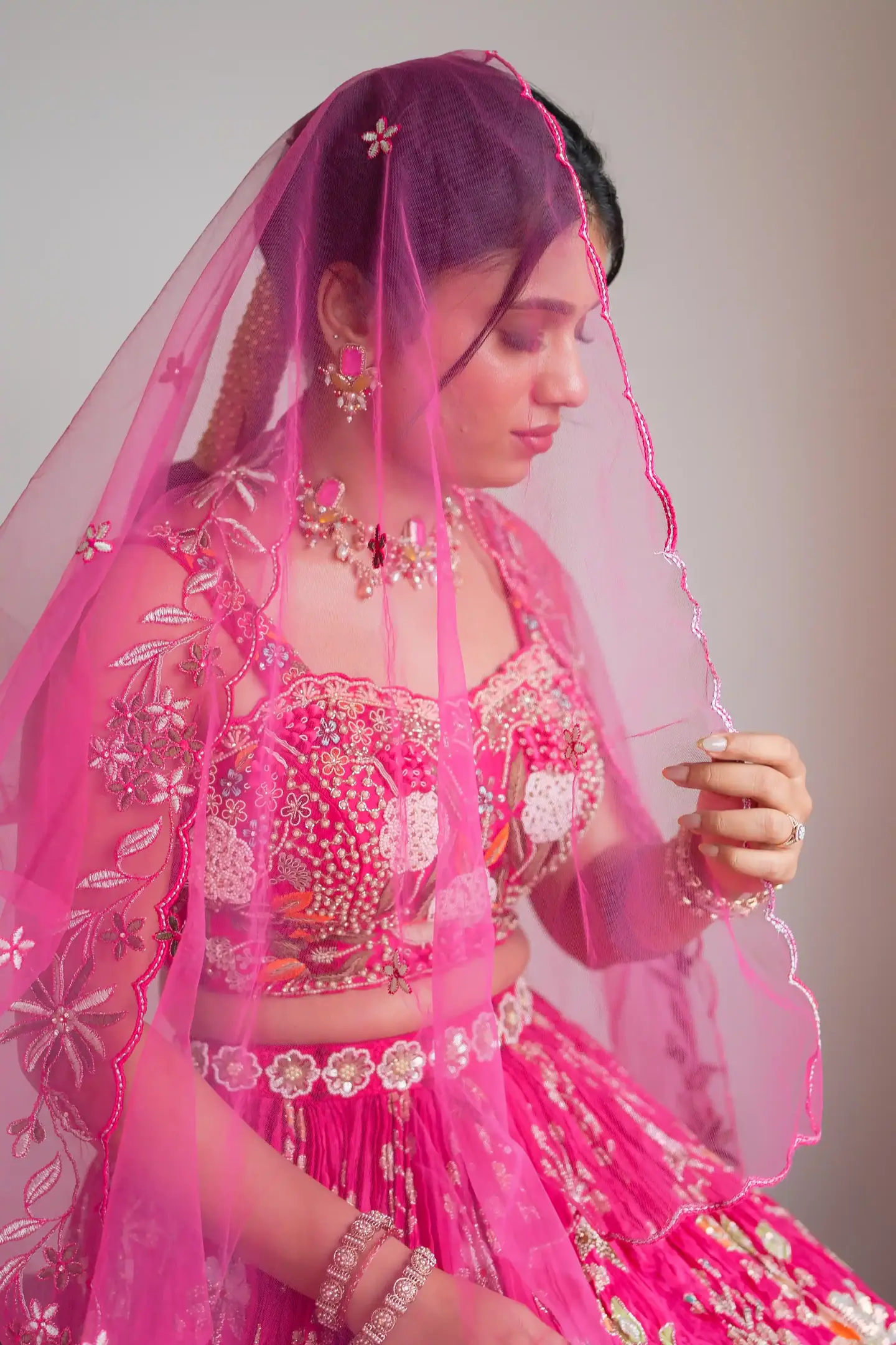 Sahana lifting a sheer pink veil
