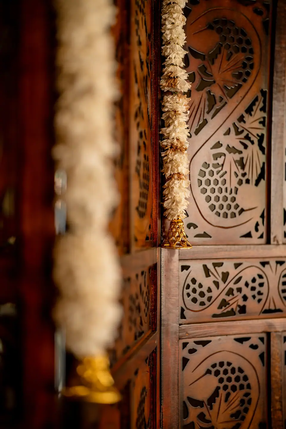 A garland of jasmine hanging against a carved wooden screen