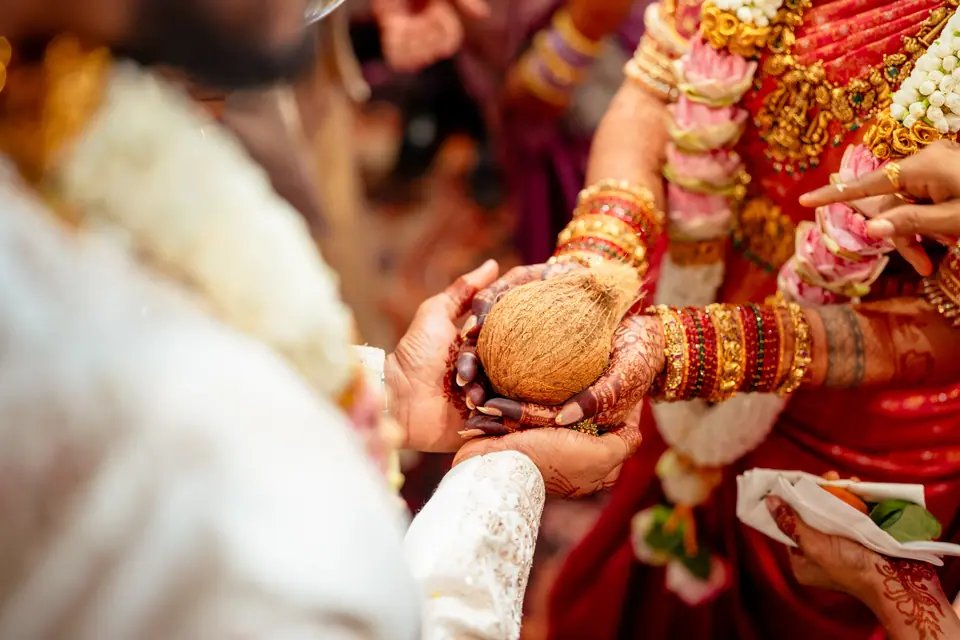 Hands passing a coconut between the bride and groom during the ceremony