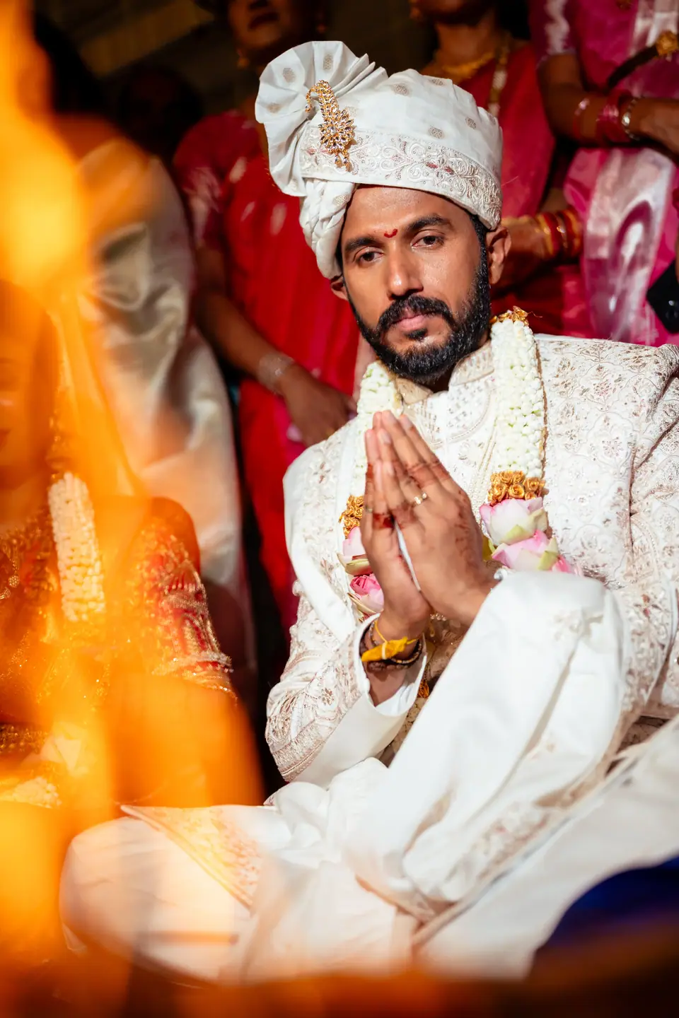 The groom with hands folded, seen through the flames of the sacred fire
