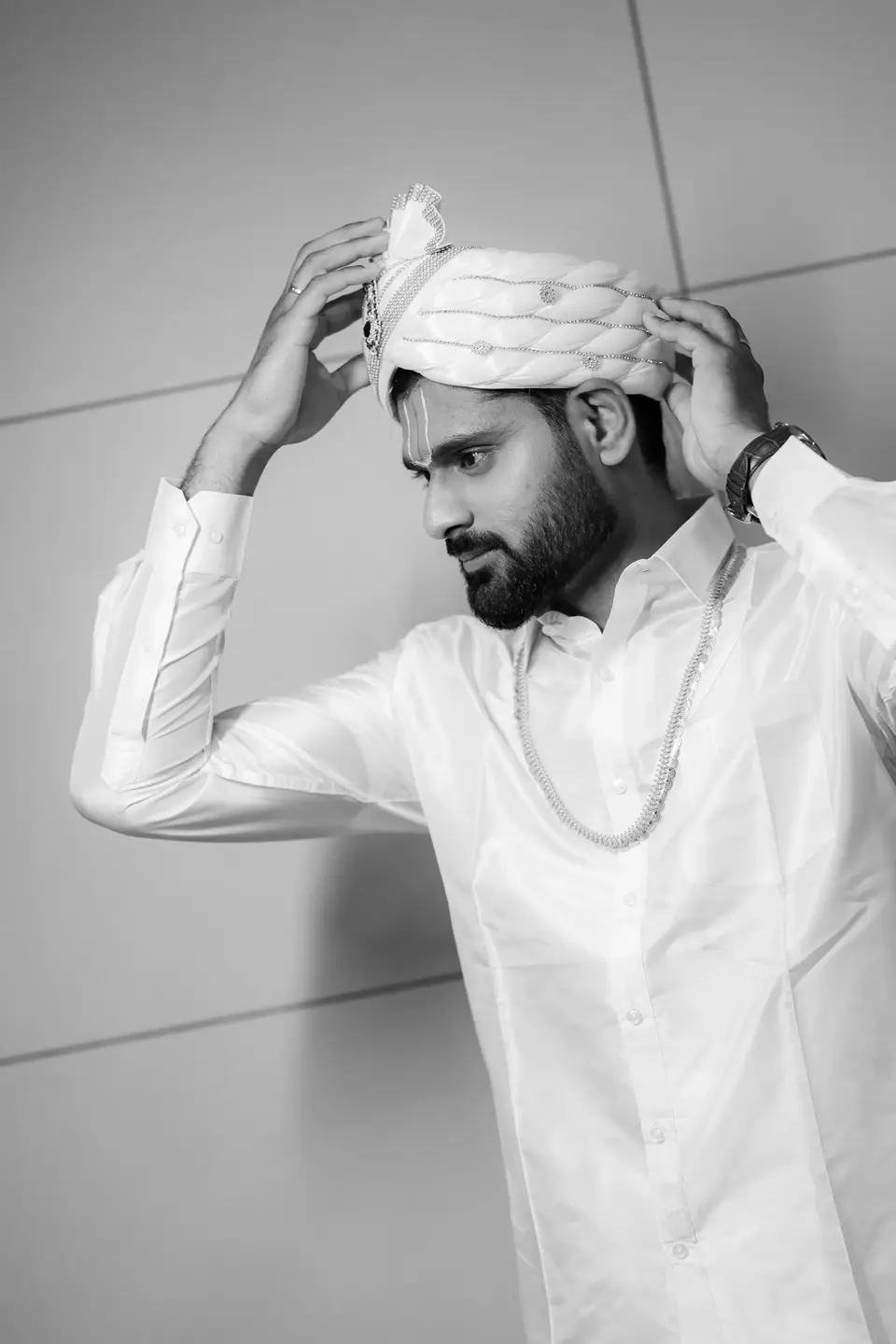 Black and white: the groom settling his turban with both hands