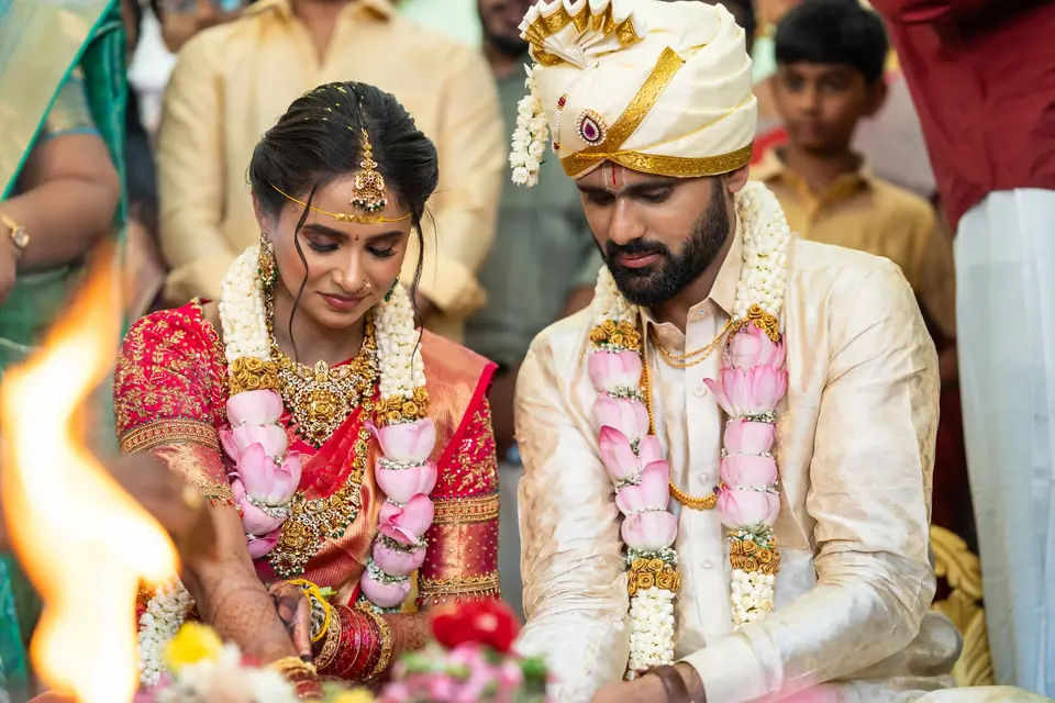 The couple seated in garlands at the ceremony, heads bowed