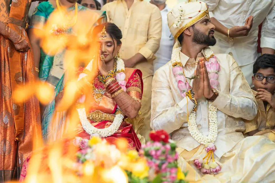 The couple with hands folded, seen through the flames of the sacred fire