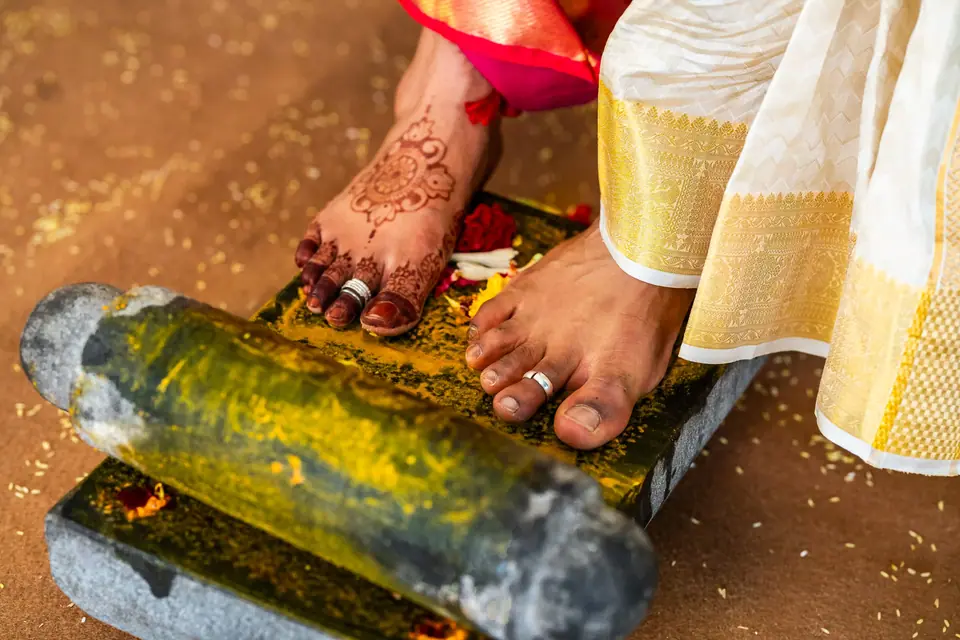 Detail of a toe ring being placed as the bride's foot rests on the grinding stone