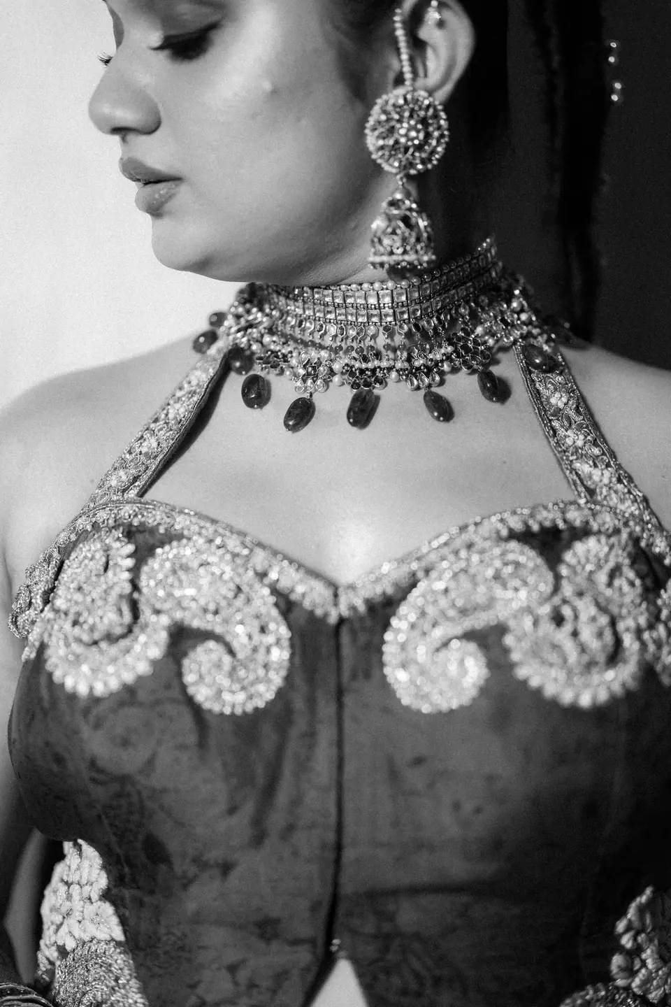 Black and white: detail of a choker of green stones above an embroidered paisley bodice