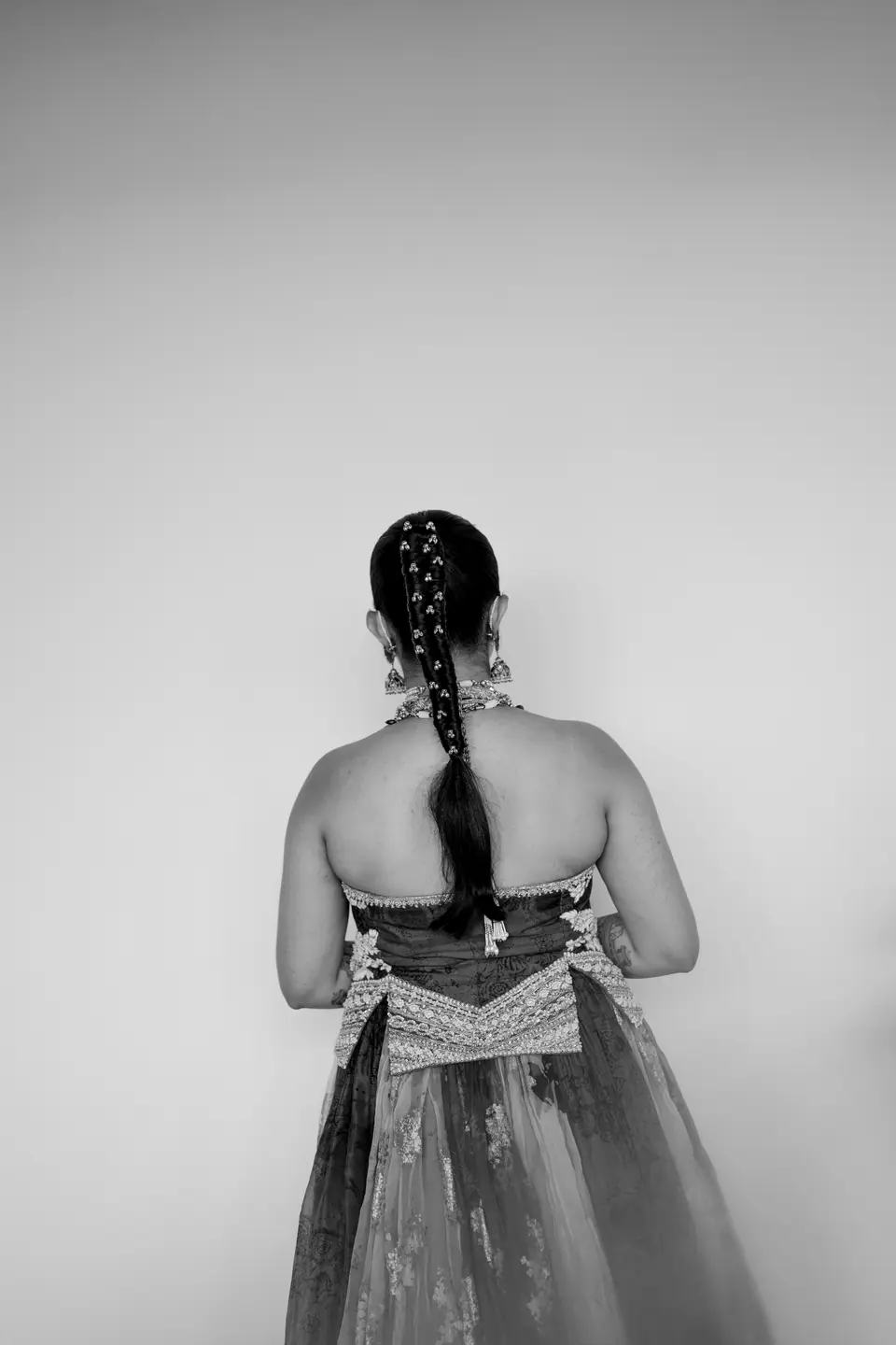 Black and white: the bride from behind, her long braid threaded with jewels