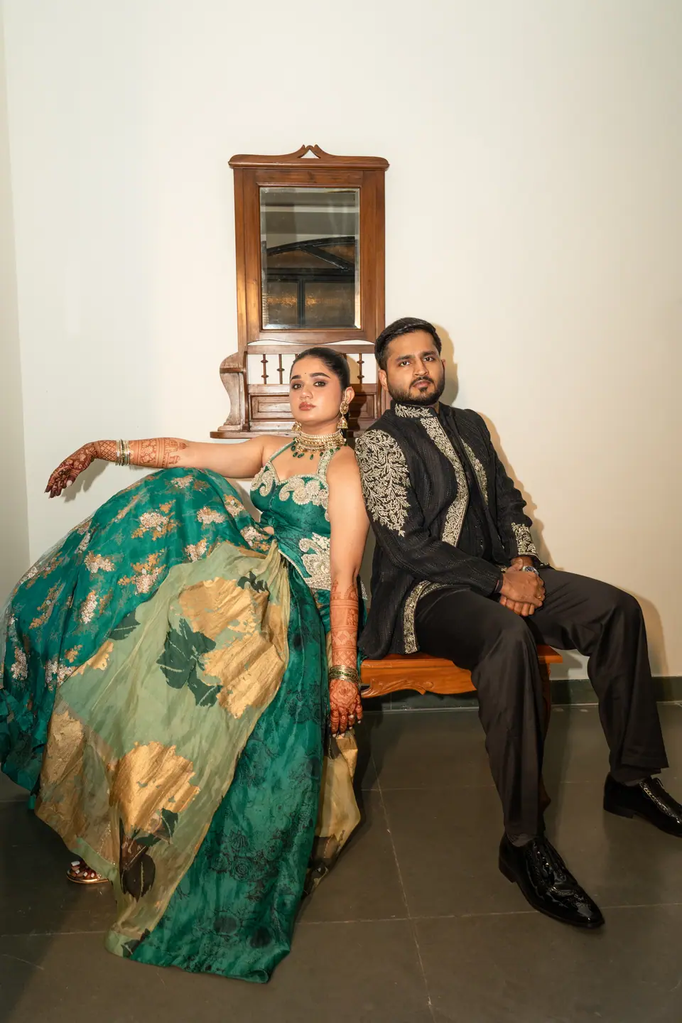 The couple seated on a carved bench, her teal skirt spread across the floor