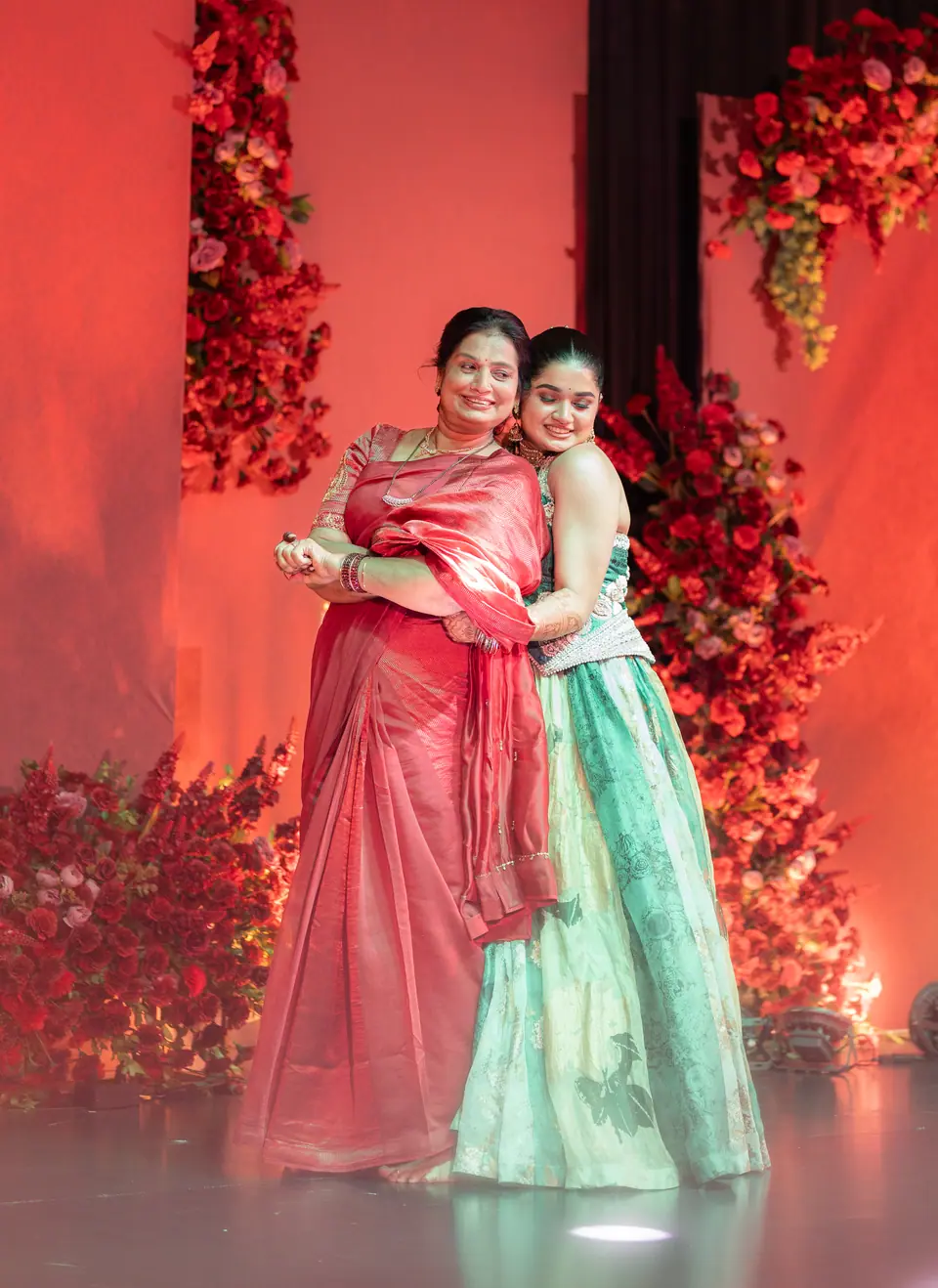 The bride embracing a woman in red silk on the stage