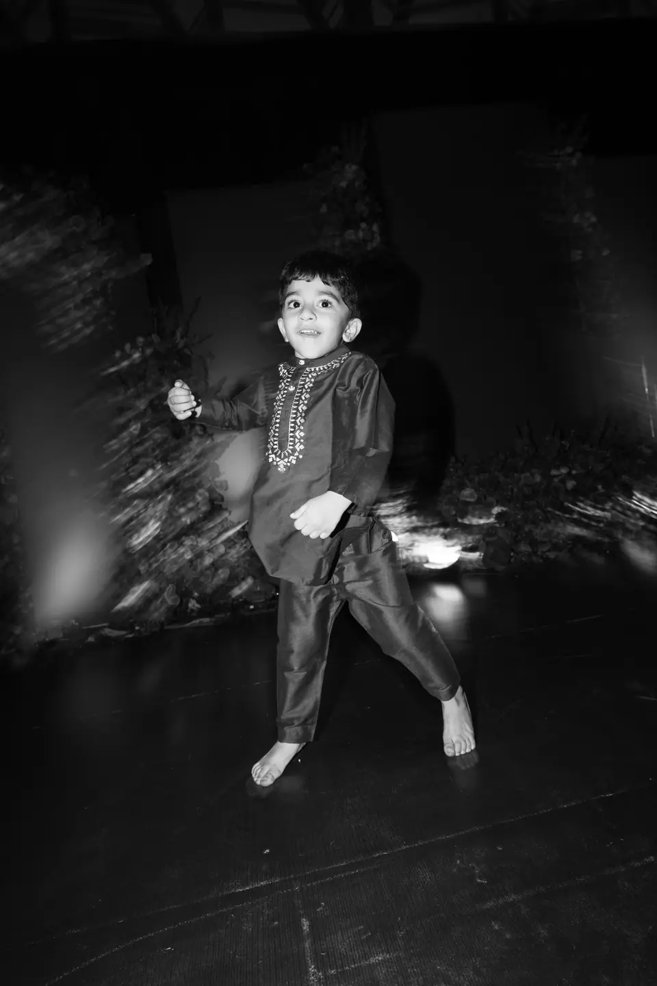 Black and white: a small boy in a kurta dancing on his own