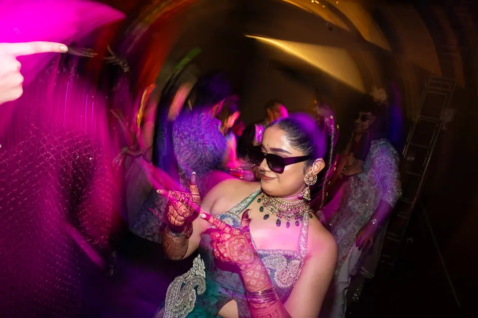 The bride in sunglasses on the dance floor under pink and violet light