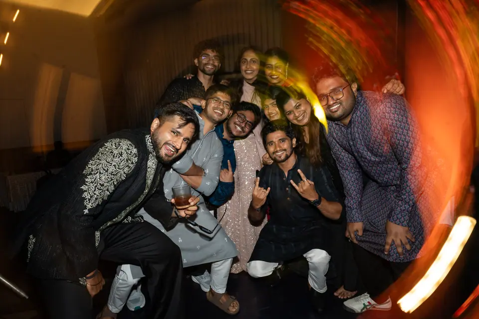 Friends crowding around the groom for a photograph, light swirling at the edges